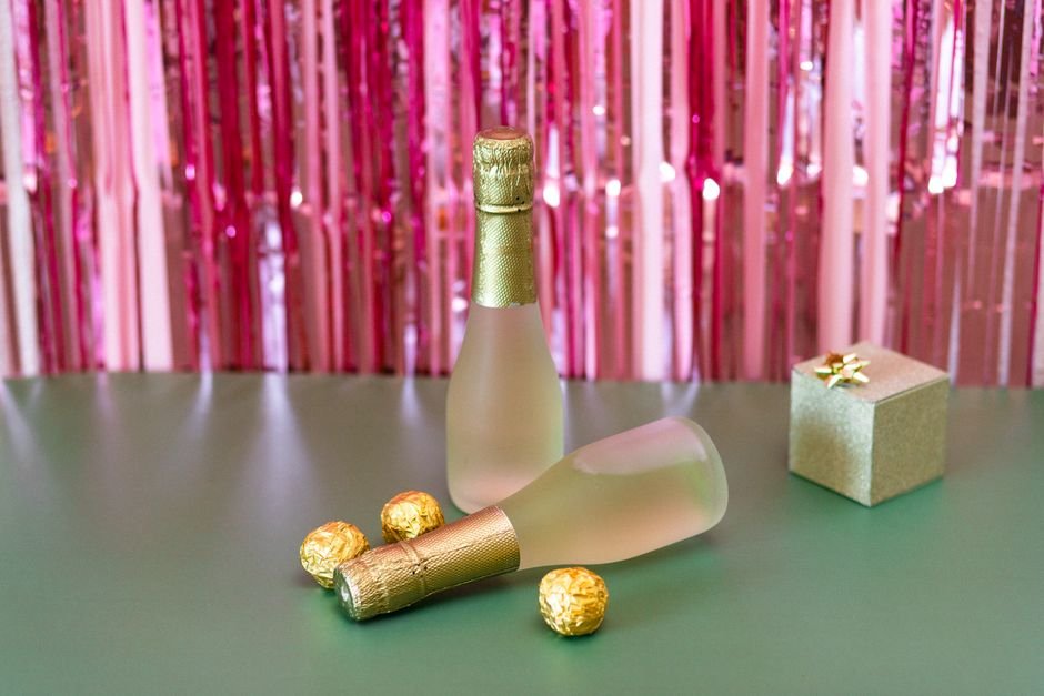 Wine bottles, chocolates, and a gift box on a festive backdrop
