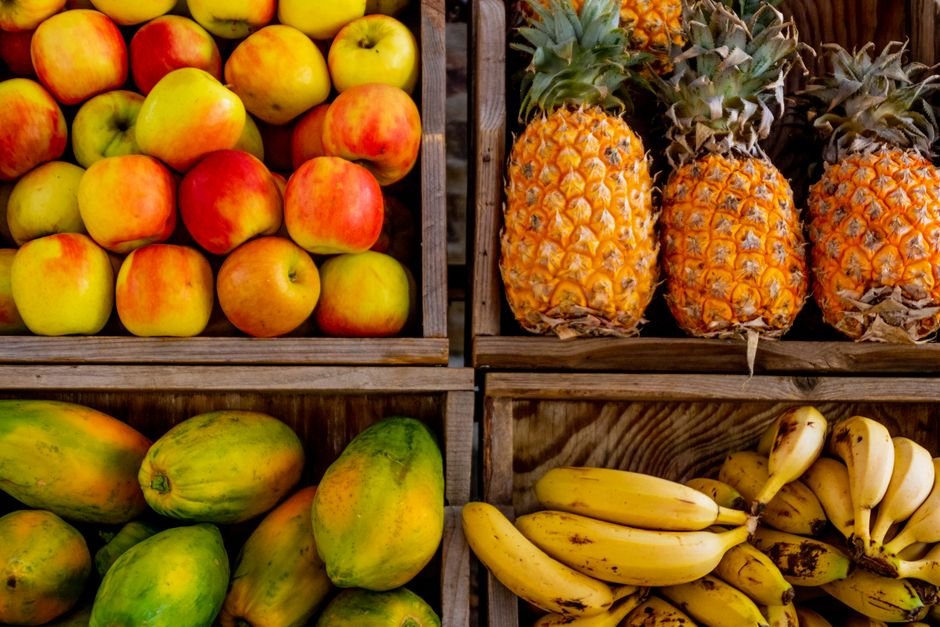 Colorful display of apples, pineapples, and bananas in wooden crates