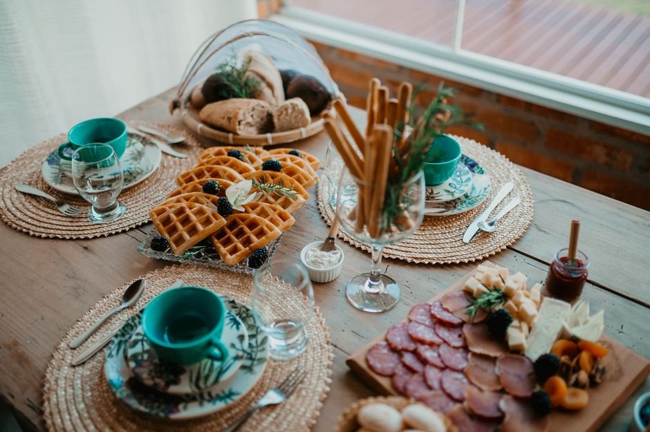 A rustic breakfast gift basket spread with waffles, charcuterie, and bread