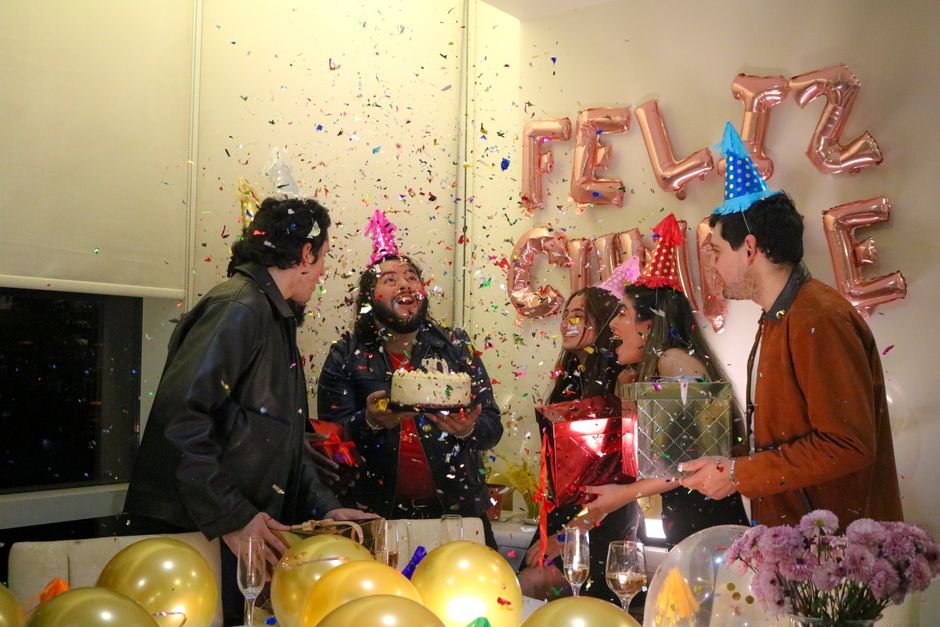 Friends celebrating a birthday together with cake and balloons, never too late to celebrate