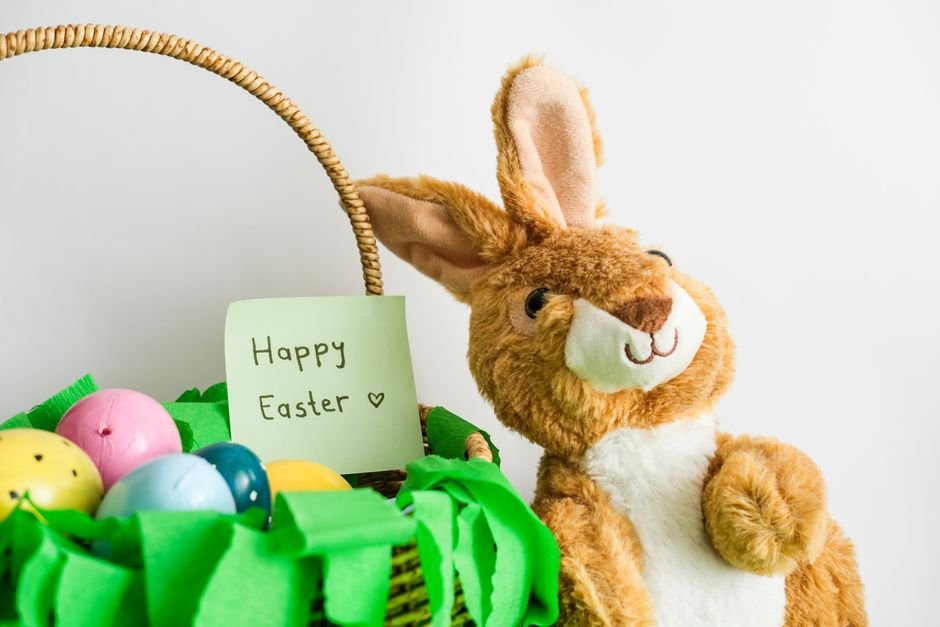 An Easter bunny plush toy beside a basket filled with colorful eggs