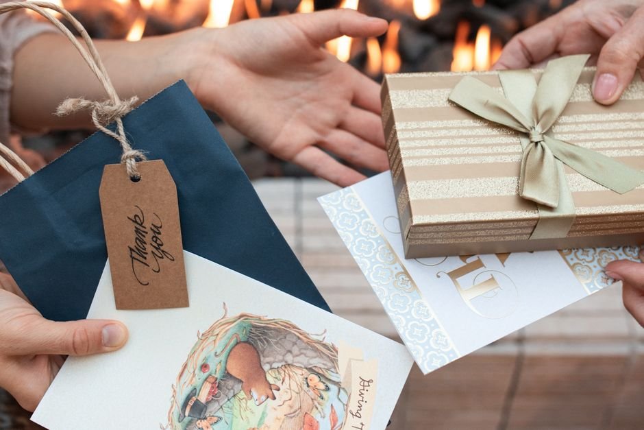 Hands exchanging a wrapped gift and a handwritten thank you card between friends