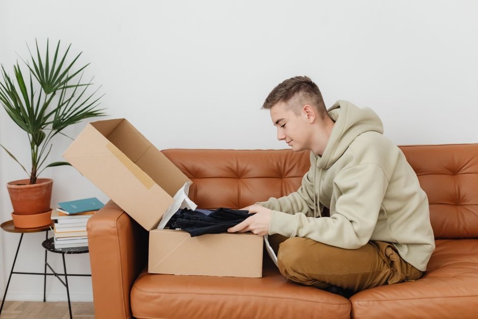 College student unboxing a college care package on a sofa