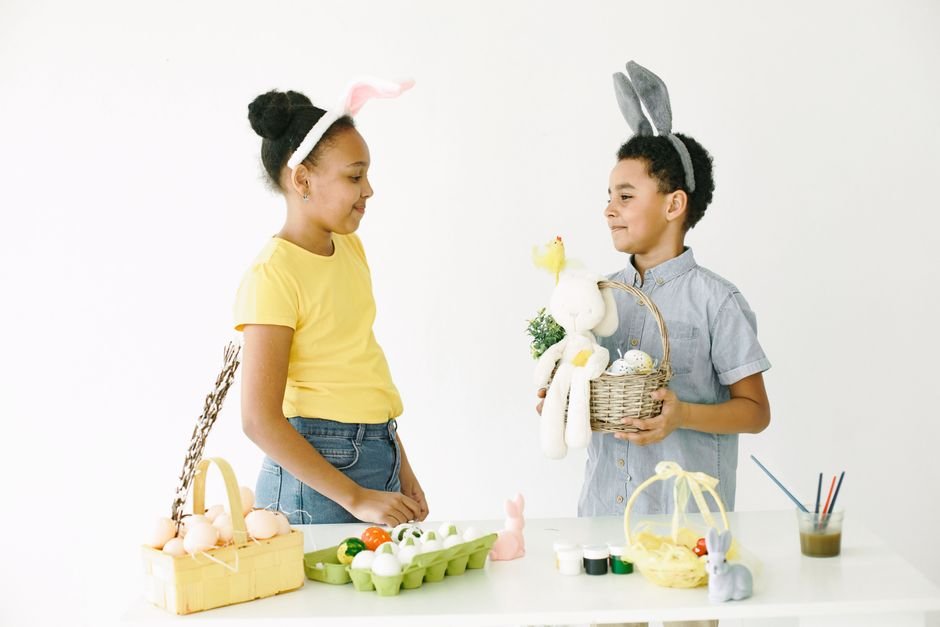 Kids decorating Easter eggs together with their gift baskets nearby