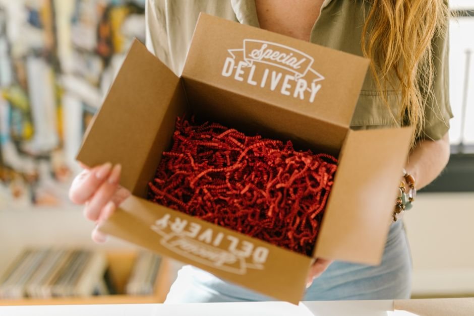 Person opening a snack gift box filled with red crinkle paper