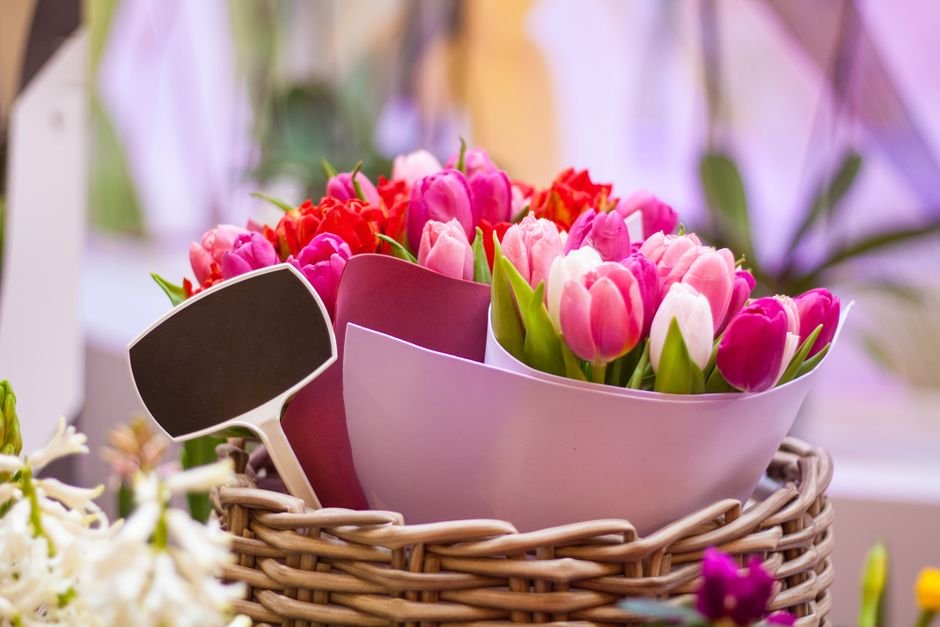 Vibrant birthday flowers arranged in a woven basket with a gift tag