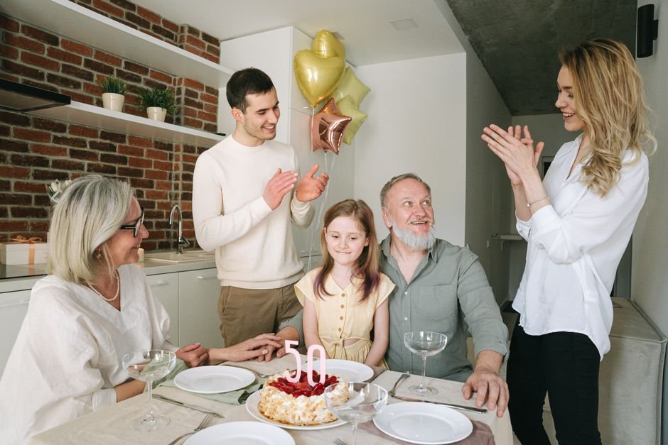 A family celebrating a milestone 50th birthday together with cake and balloons