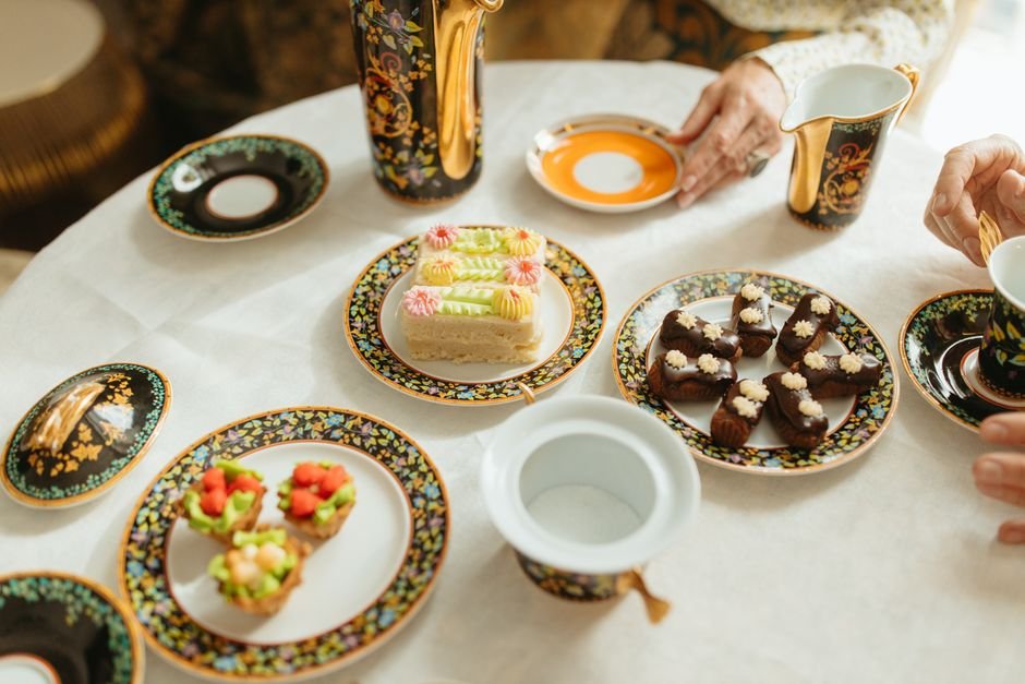 An afternoon tea setup with elegant china cups and a plate of gourmet pastries