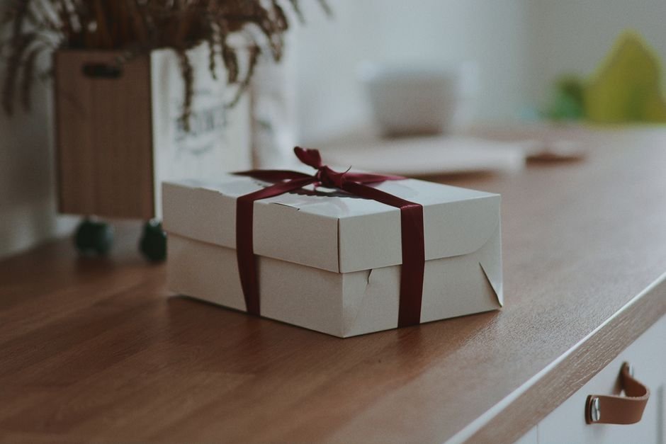 White gift box with a red ribbon on a wooden surface