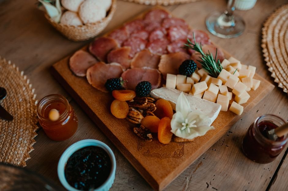 A charcuterie gift basket spread with cheese, meats, and fresh fruit
