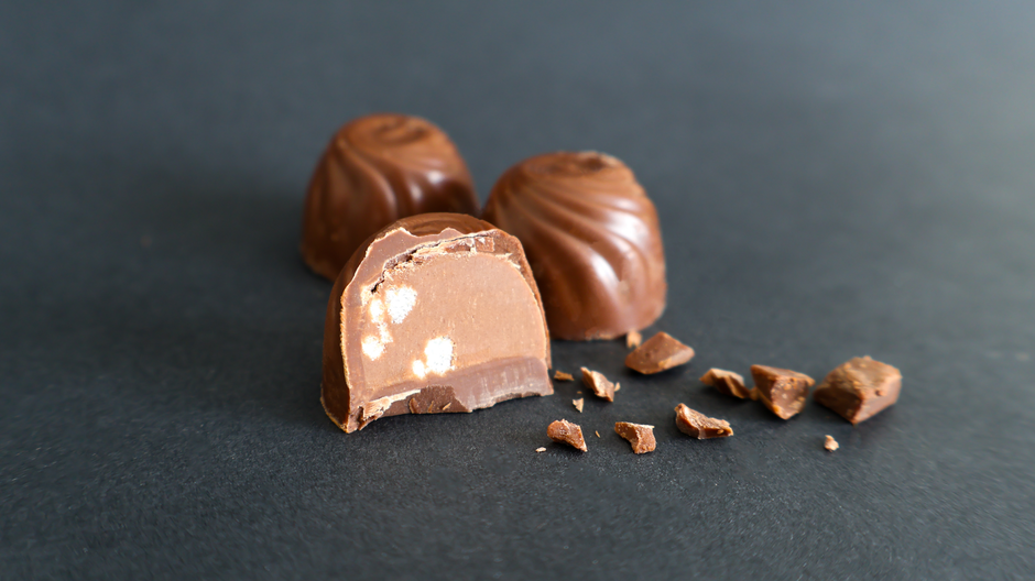 Milk chocolate truffle bitten open showing the creamy melting center