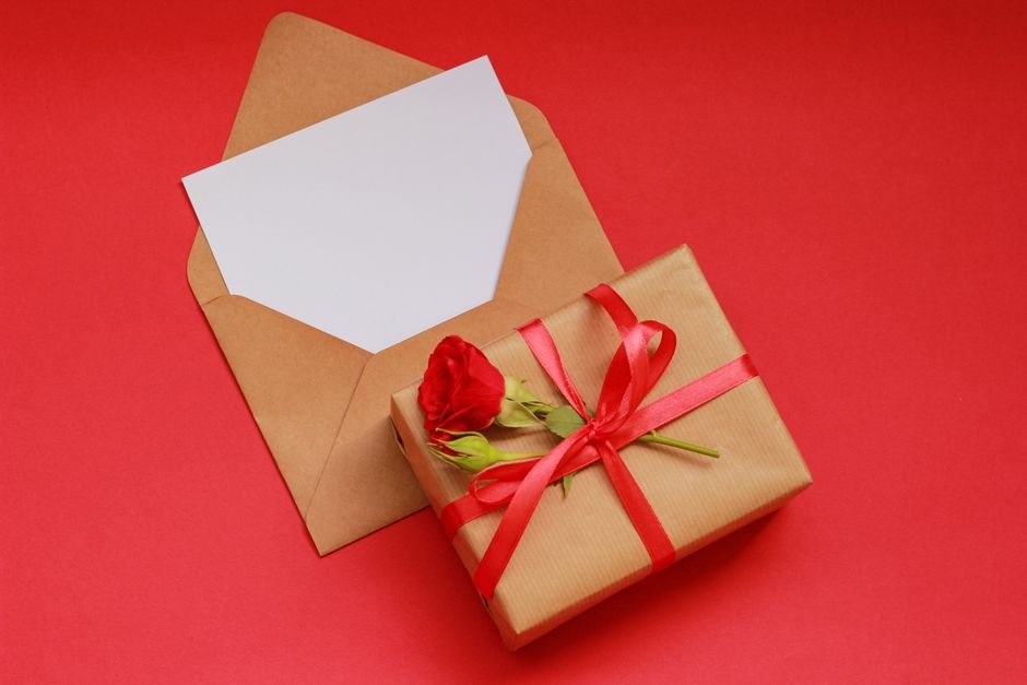 A blank card and envelope beside a wrapped gift, ready for an engagement card message