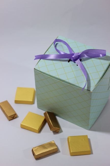 Gold wrapped chocolate candies beside an open candy gift box