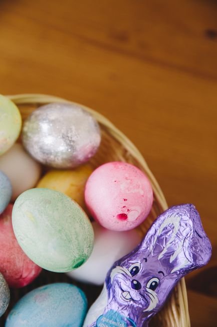 Pastel Easter eggs and a foil wrapped chocolate bunny in a wicker basket