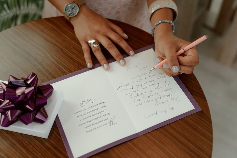 Woman writing a heartfelt message inside a sympathy card