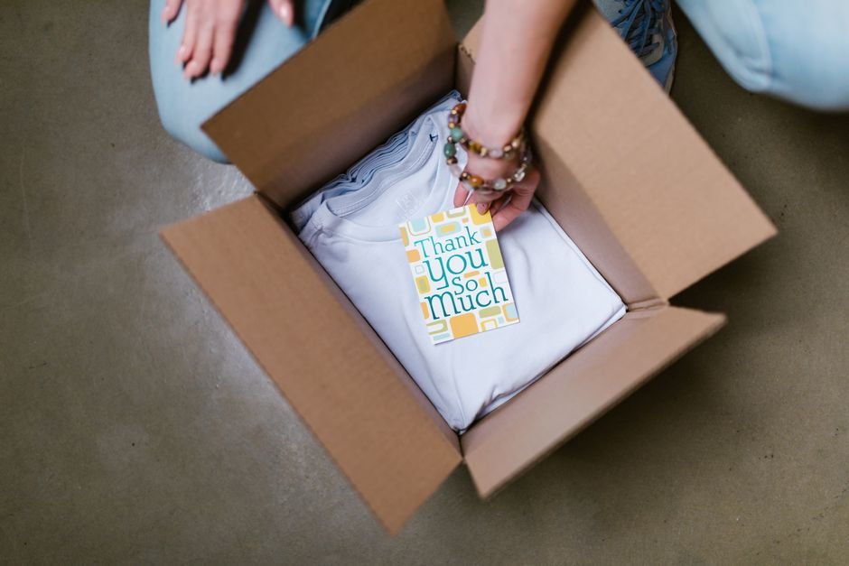 Person packing a subscription box with a thank you card