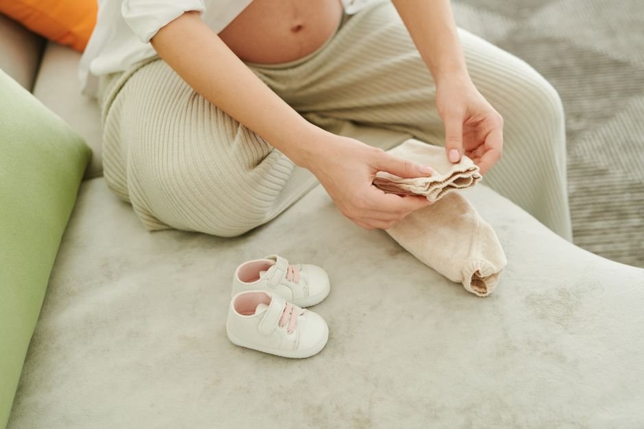 Pregnant woman folding baby socks for a pregnancy care package